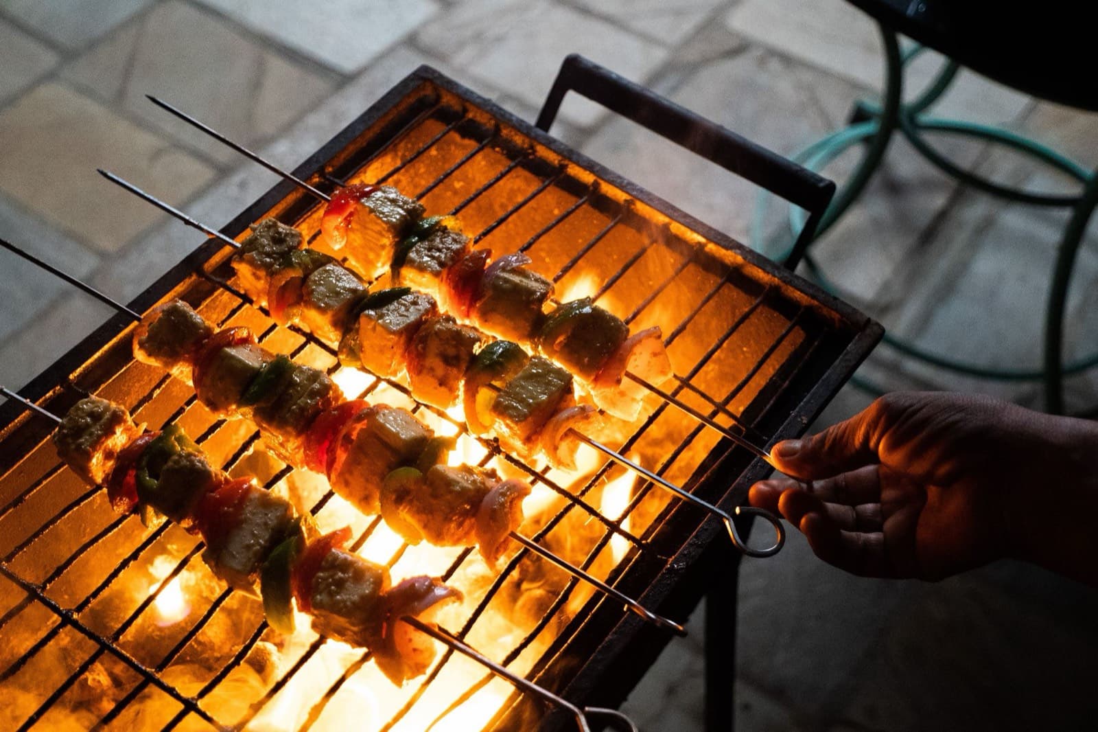 Churrasqueira de quintal com espetos sobre a brasa